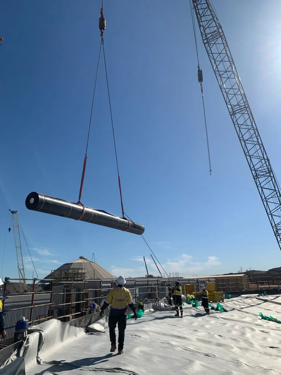 Installation crew working liner panels down a prepared batter slope