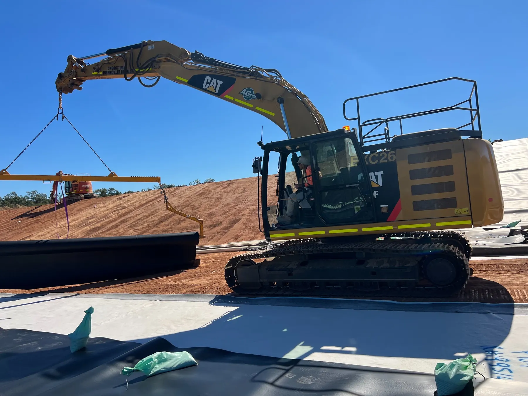 Machinery deploying a roll of HDPE geomembrane liner across prepared subgrade